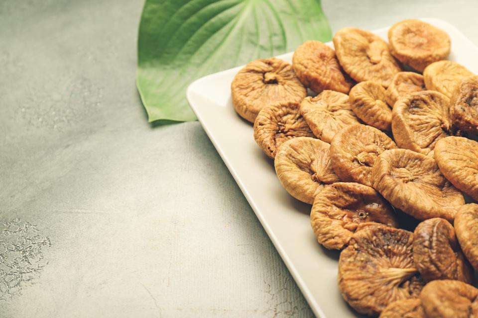 Plate with tasty dried figs on color background