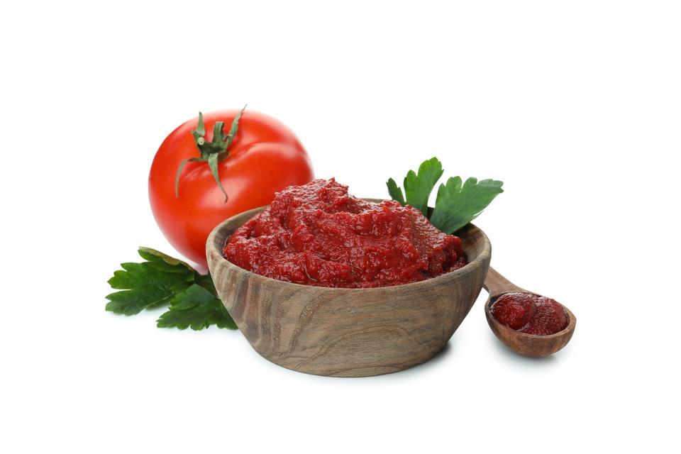 Wooden bowl and spoon with tomato paste isolated on white background