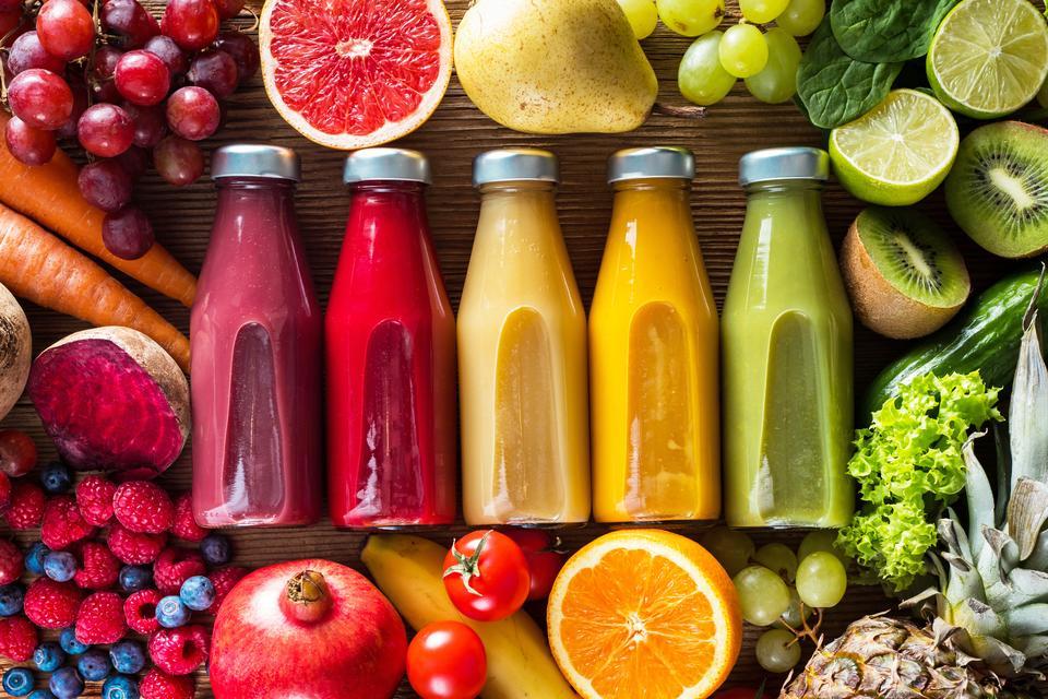 Colorful smoothies in bottles and fresh fruits and vegetables on wooden table, top view.