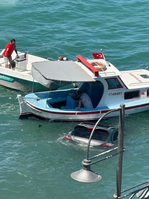 AYVALIK'TA OTOMOBİL DENİZE UÇTU ARAÇ SÜRÜCÜSÜ BATAN ARACIN ÜZERİNDE DAKİKALARCA KURTARILMAYI BEKLEDİ